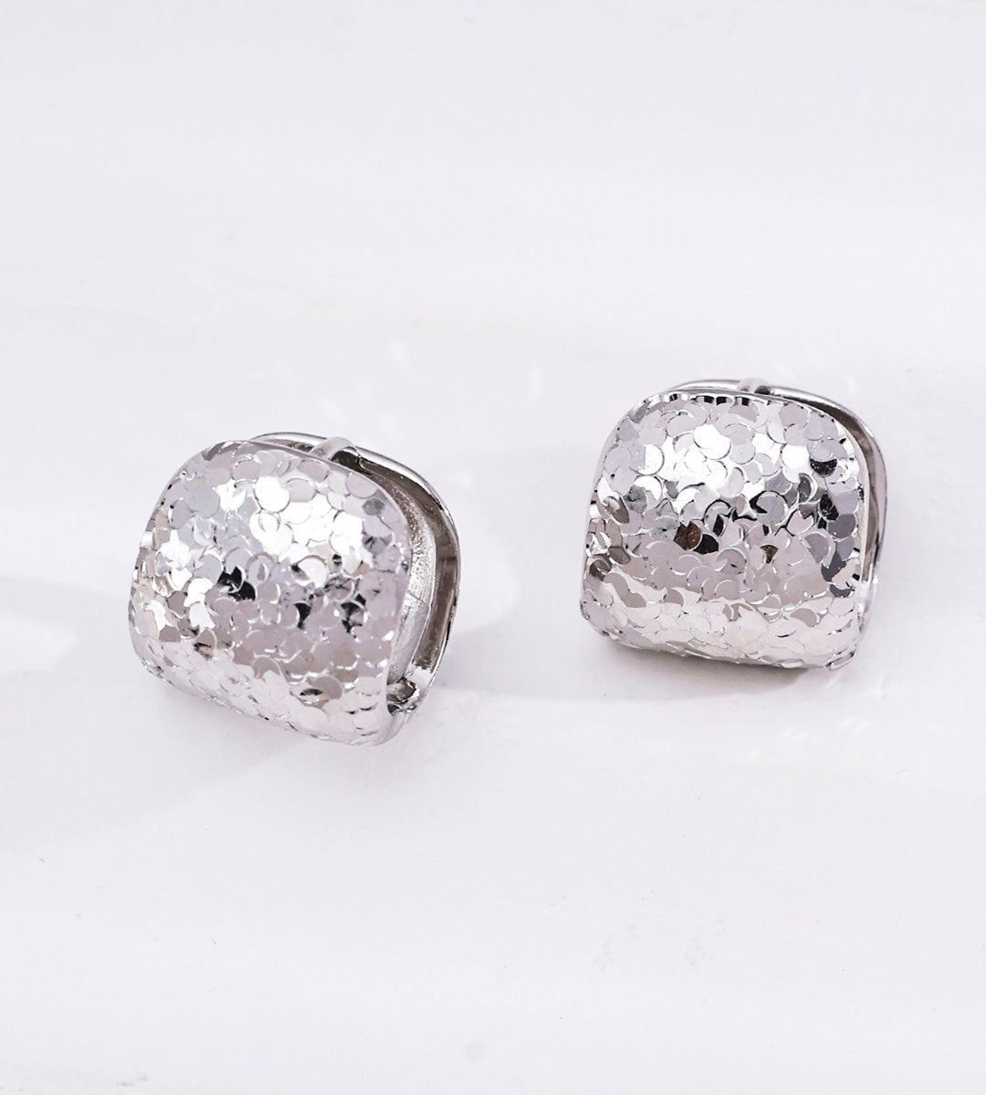 A pair of silver-toned Pillow Huggie Earrings with a textured, glitter finish 18K Gold Plated S925 Silver | BUCKLE Collective