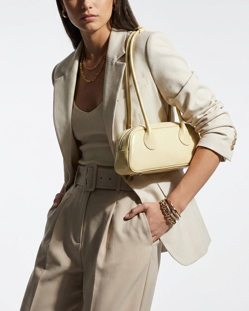 Elegant Woman in a stylish, fashionable outfit wearing a chic genuine leather shoulder baguette bag in a yellow cream color