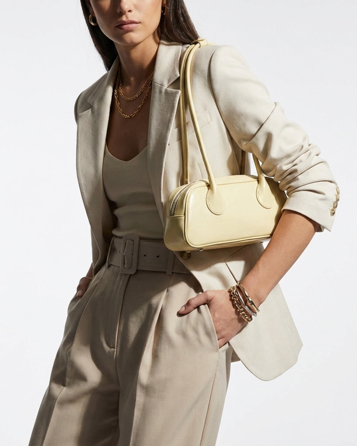 Elegant Woman in a stylish, fashionable outfit wearing a chic genuine leather shoulder baguette bag in a yellow cream color