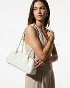 Elegant Woman in a stylish light outfit wearing a chic genuine leather baguette shoulder bag in a white color