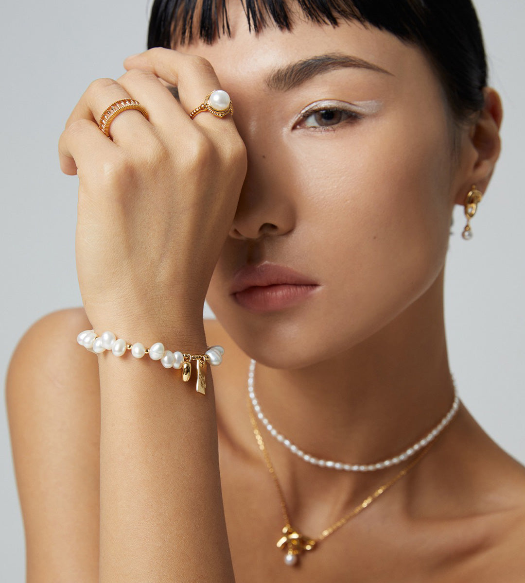 Good Luck baroque freshwater pearl bracelet in vintage gold — editorial model wearing "Good Luck" charm bracelet with pearl choker necklace and gold pearl earrings, BUCKLE Collective