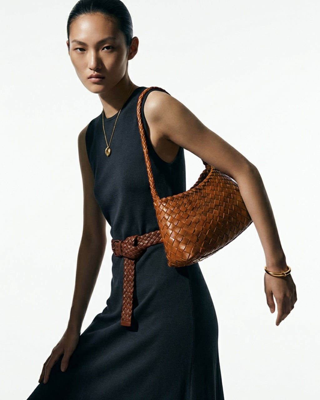 Woman in a stylish minimalist dress with a woven buffalo leather shoulder bag in yellow-brown color
