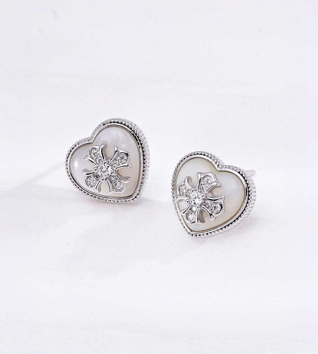 Silver tone heart shaped mother-of-pearl stud earrings with cubic zirconia-set flower centres and finely beaded metal borders.