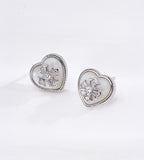 Silver tone heart shaped mother-of-pearl stud earrings with cubic zirconia-set flower centres and finely beaded metal borders.