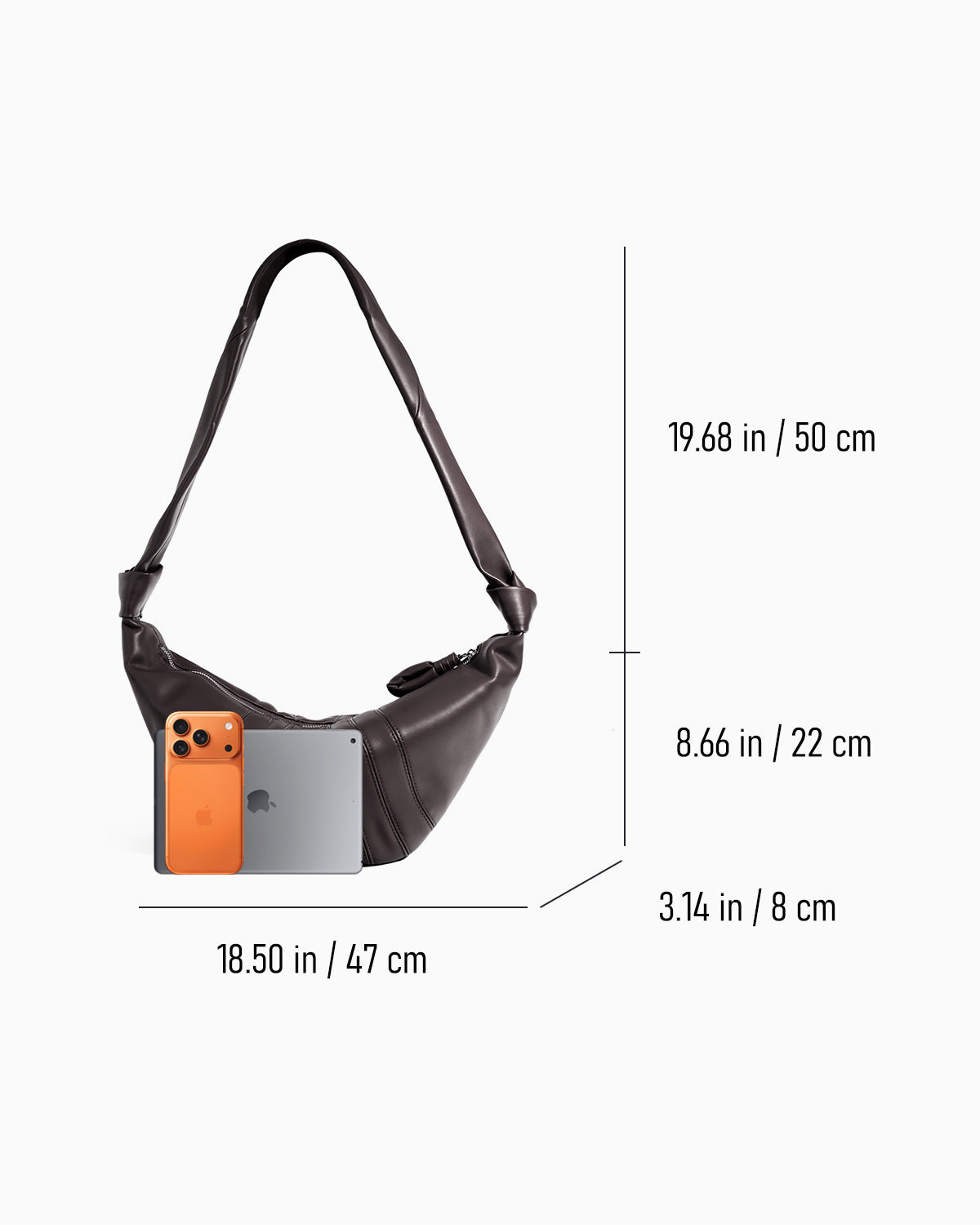 A dark brown crescent-shaped shoulder bag shown on a light gray background with dimension lines and measurements indicating width, height, and strap length. Smartphone and tablet are placed in front of the bag for scale | BUCKLE Collective