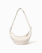 An off-white, large genuine lambskin leather crescent-shaped shoulder bag with a single strap and a zippered top | BUCKLE Collective