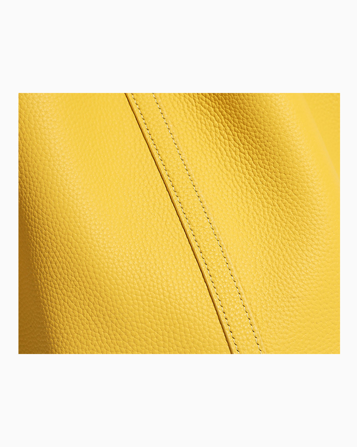 A close-up of a bright yellow pebbled leather surface with a diagonal stitched seam running through the center
