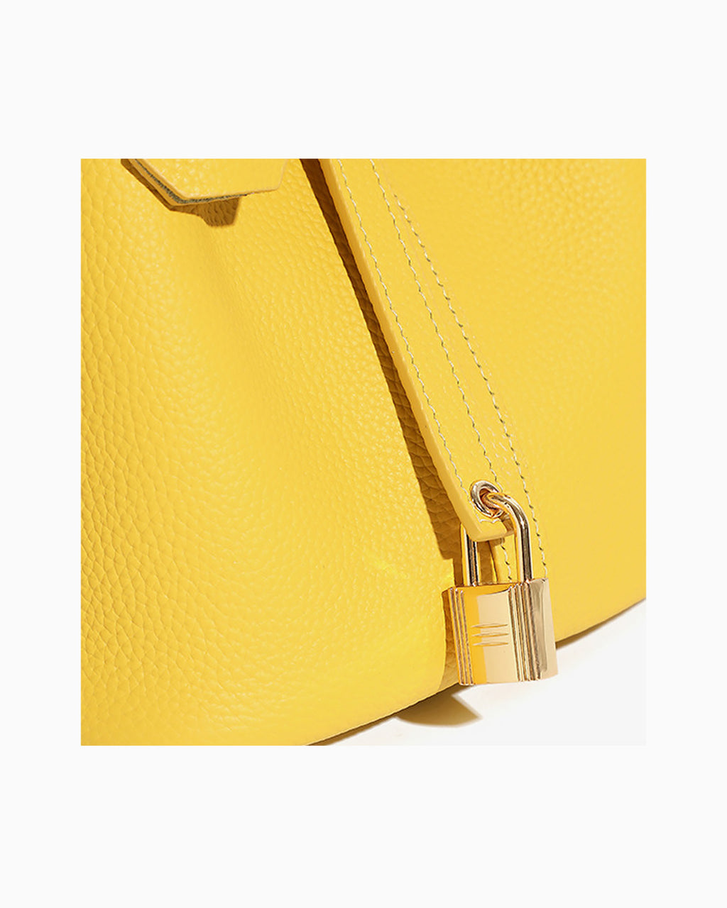Close-up of a bright yellow pebbled leather bucket handbag with a gold padlock and strap detail