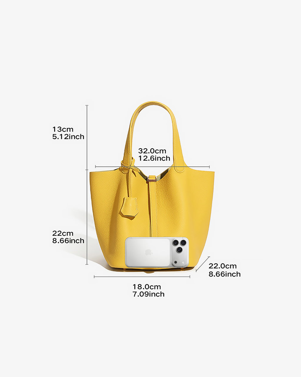 Large Yellow Genuine Togo Leather Bucket Bag with Lock with dimension callouts showing height, width, and depth measurements, plus a white smartphone placed inside the bag for scale, on a light gray background.