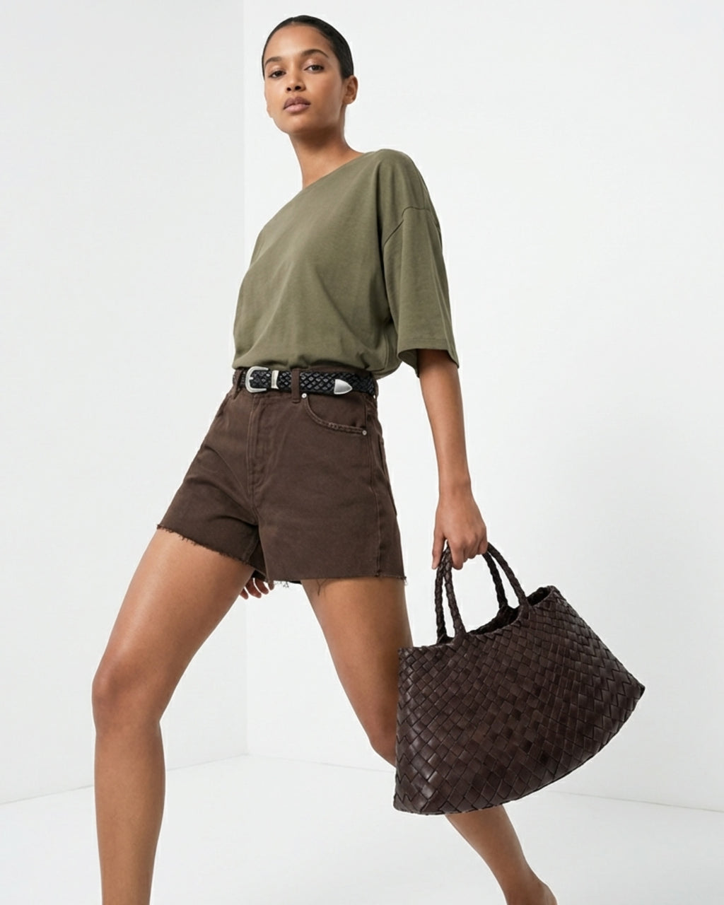 A woman in a casual outfit carries a Trendy & Spacious Genuine Leather Woven Handbag with Removable Pouch in Coffee Color
