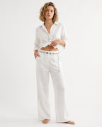 A woman in a white two-piece outfit consisting of a cropped, tie-front button-up shirt and matching wide-leg trousers with a decorative silver BOHO Style Leaf Chain Waist Belt | BUCKLE Collective