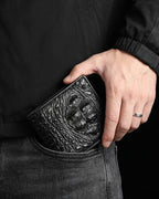 A close-up of a person's hand holding a black Genuine Crocodile Leather Wallet in their pocket, wearing a black jacket and dark gray jeans.