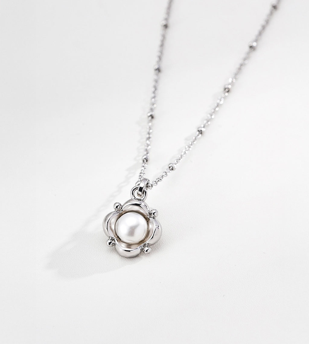 Flower natural pearl pendant necklace close-up — silver-tone sculpted floral frame with 6mm natural freshwater pearl centre, fine beaded satellite chain, 18K white gold plated S925 sterling silver, BUCKLE Collective