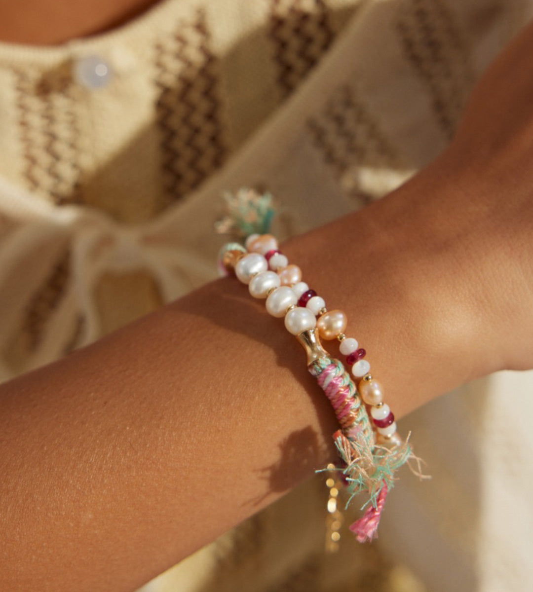 Natural pearl ethnic braided bracelet worn stacked on wrist — multicolour cord with bamboo gold connectors and freshwater pearls, layered with pink cord bracelet, boho beach style, BUCKLE Collective