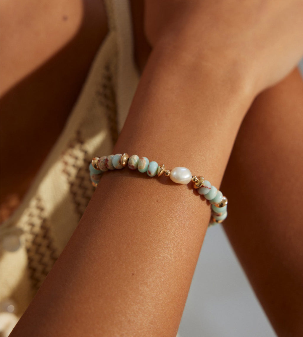 Natural Pearl Shoushan stone bracelet worn on wrist — sky-blue stone beads, freshwater pearl centre, and gold spacer accents, 18K gold plated S925 sterling silver, boho coastal style, BUCKLE Collective