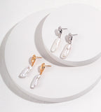 Baroque freshwater pearl drop earrings in Vintage Gold and White Gold finishes on stacked circular white displays.