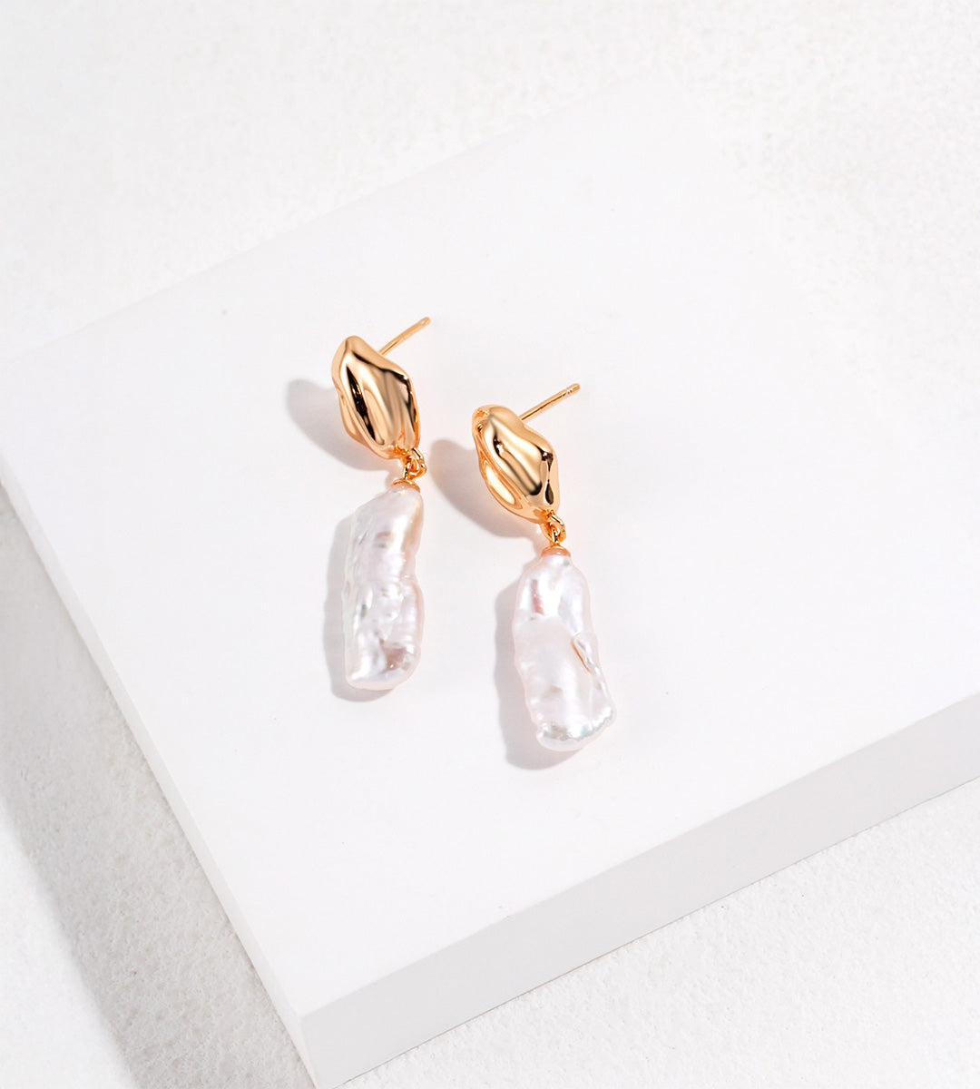 Angled view of 18K gold-plated S925 silver baroque pearl drop earrings, showing fluid-shaped tops and ear posts.