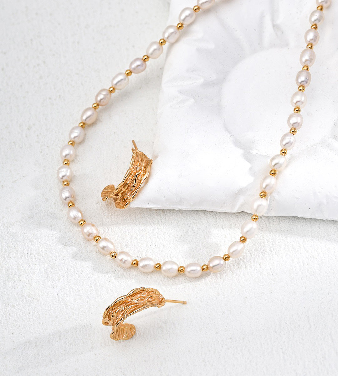 18K gold-plated and white pearl jewelry set featuring a delicate necklace and matching earrings, displayed on a soft white fabric background.