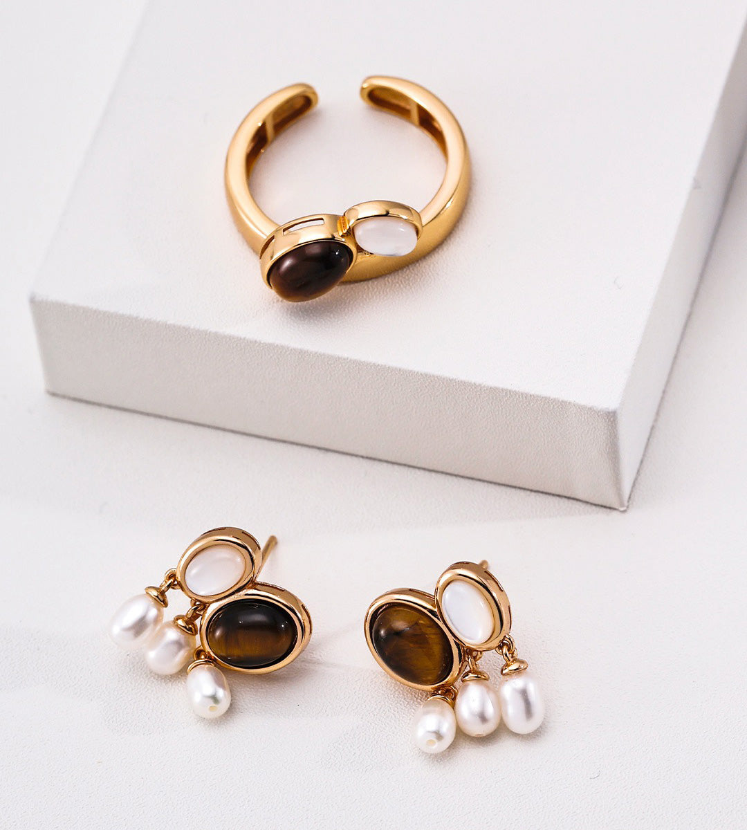 18K Gold-plated jewelry set featuring a curved ring and matching drop earrings, each with an oval tiger's eye gemstone and three dangling white pearl beads