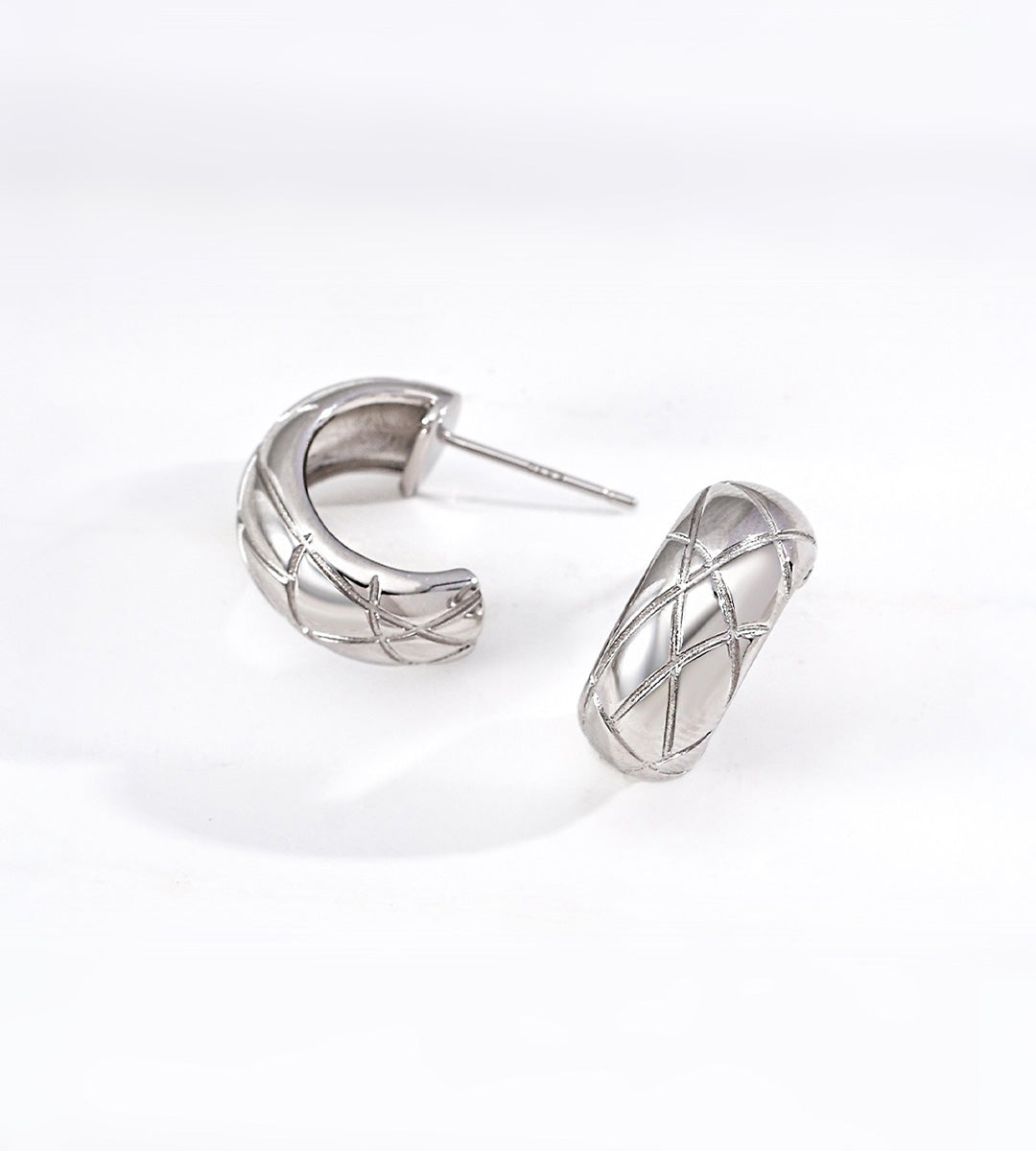 A pair of 18K white-gold-plated S925 silver huggie hoop earrings with a textured, quilted diamond pattern, displayed on a clean white background.