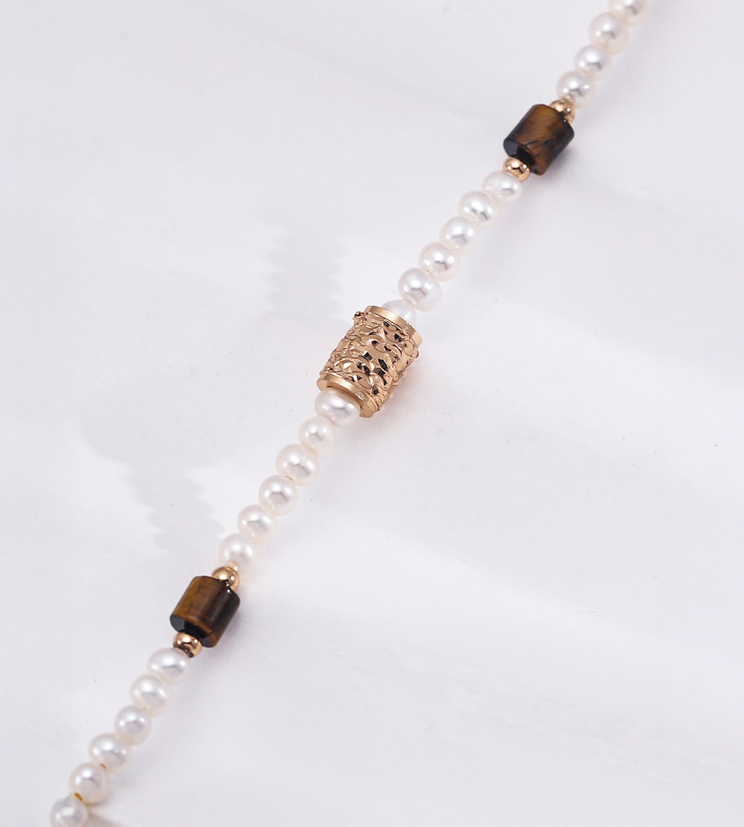 Natural pearl and tiger's eye bracelet close-up — ornate filigree engraved gold barrel bead with cut-work detail, rectangular tiger's eye gemstone beads, freshwater pearls, 18K gold plated S925 silver, BUCKLE Collective