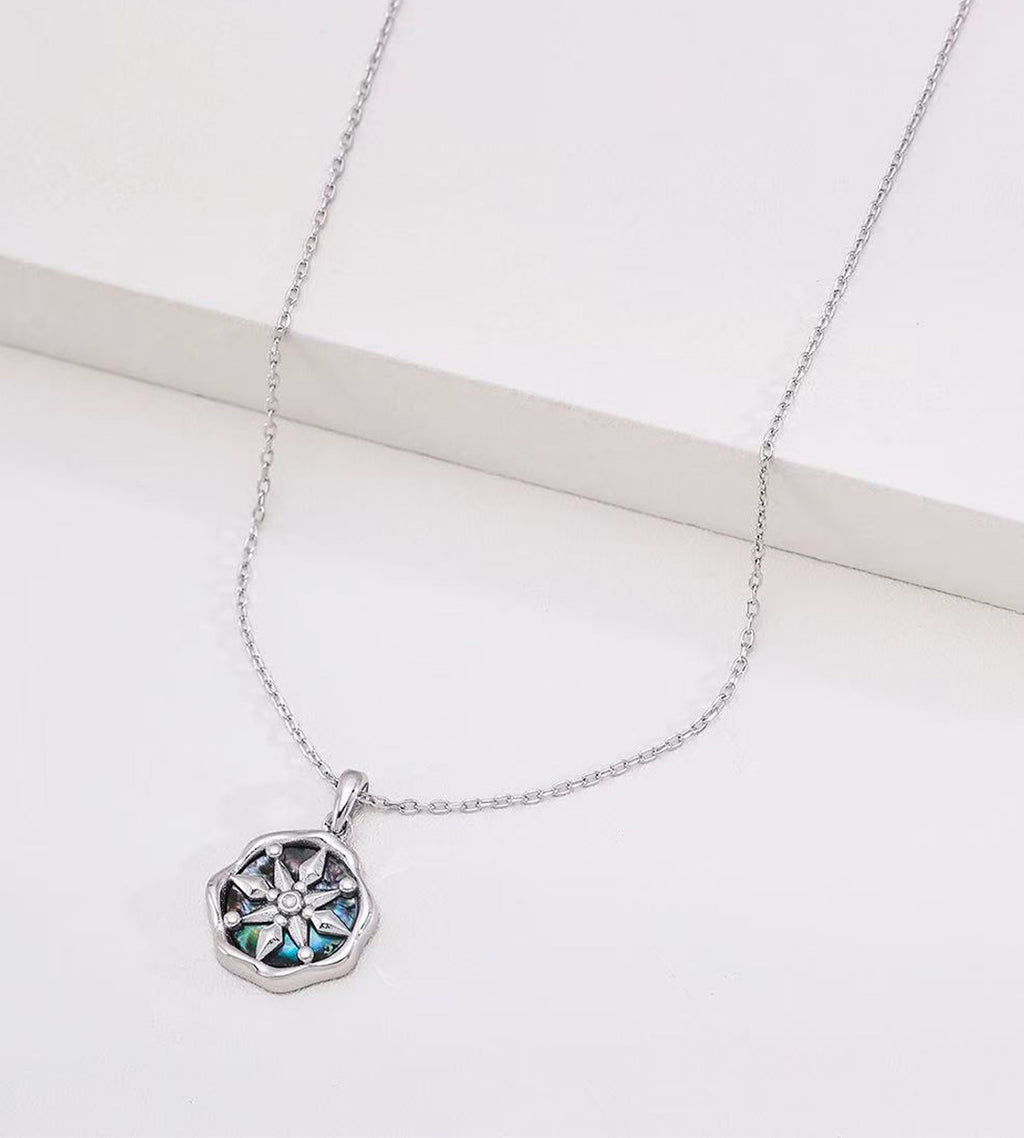 Abalone shell star compass necklace in white gold plating — eight-pointed compass motif with iridescent shell inlay, wavy octagonal border, adjustable cable chain, S925 sterling silver, BUCKLE Collective