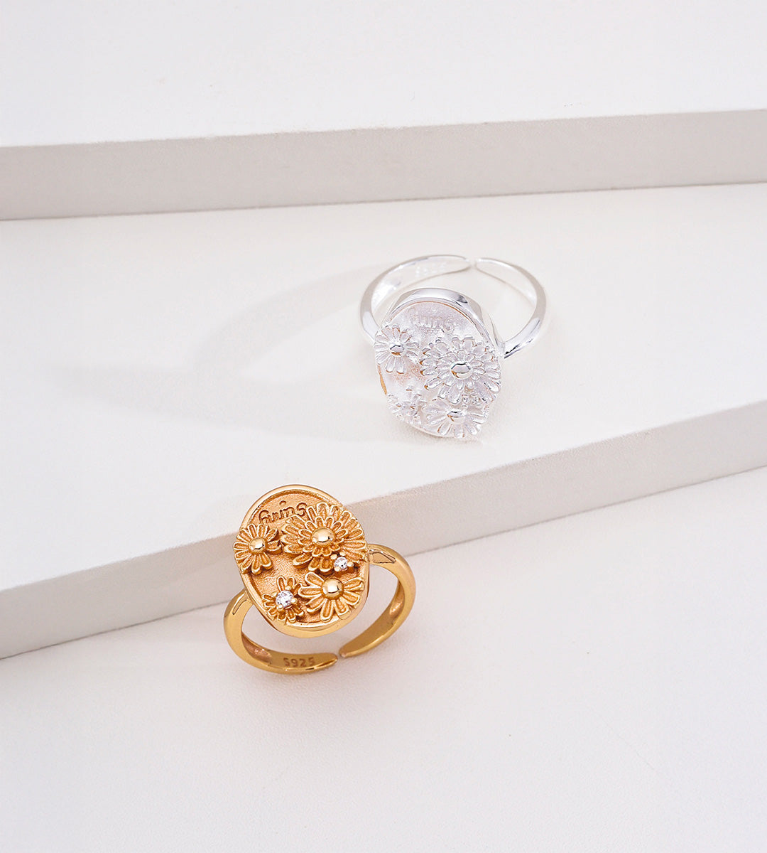 Sunny Daisy embossed open ring in vintage gold and natural silver tone — both colourways shown side by side, 3D daisy signet plaque with engraved "sunny" lettering and CZ accents, adjustable band, S925 sterling silver, BUCKLE Collective