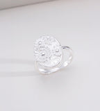 Sunny Daisy embossed open ring in natural silver tone — 3D raised daisy floral oval signet plaque with engraved "sunny" lettering, adjustable open band, 18K plated S925 sterling silver, BUCKLE Collective