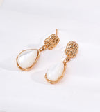 A pair of 18K gold-plated S925 silver drop earrings featuring textured, organic-shaped gold tops and teardrop-shaped white mother-of-pearl dangles | BUCKLE Collective