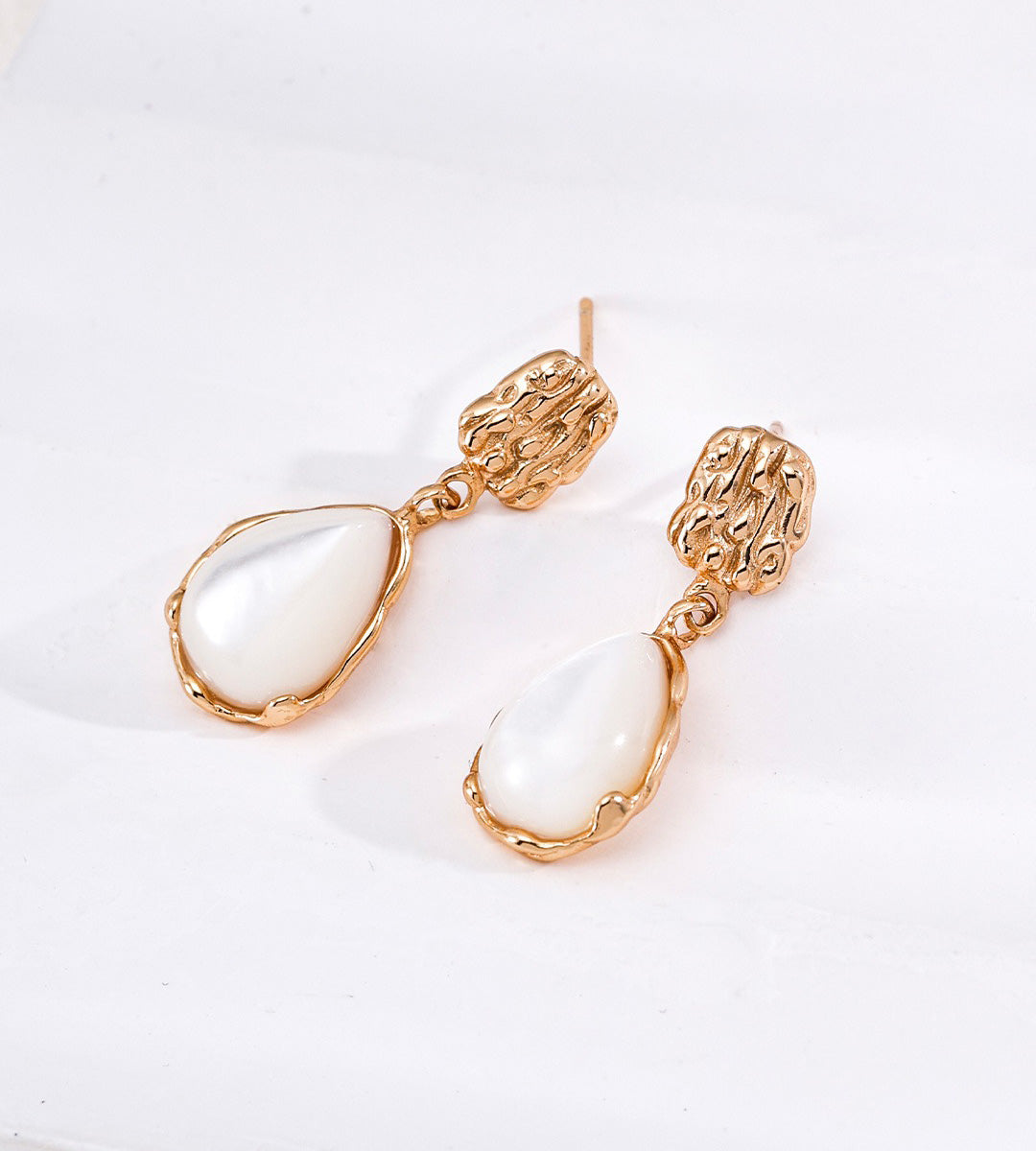 A pair of 18K gold-plated S925 silver drop earrings featuring textured, organic-shaped gold tops and teardrop-shaped white mother-of-pearl dangles | BUCKLE Collective