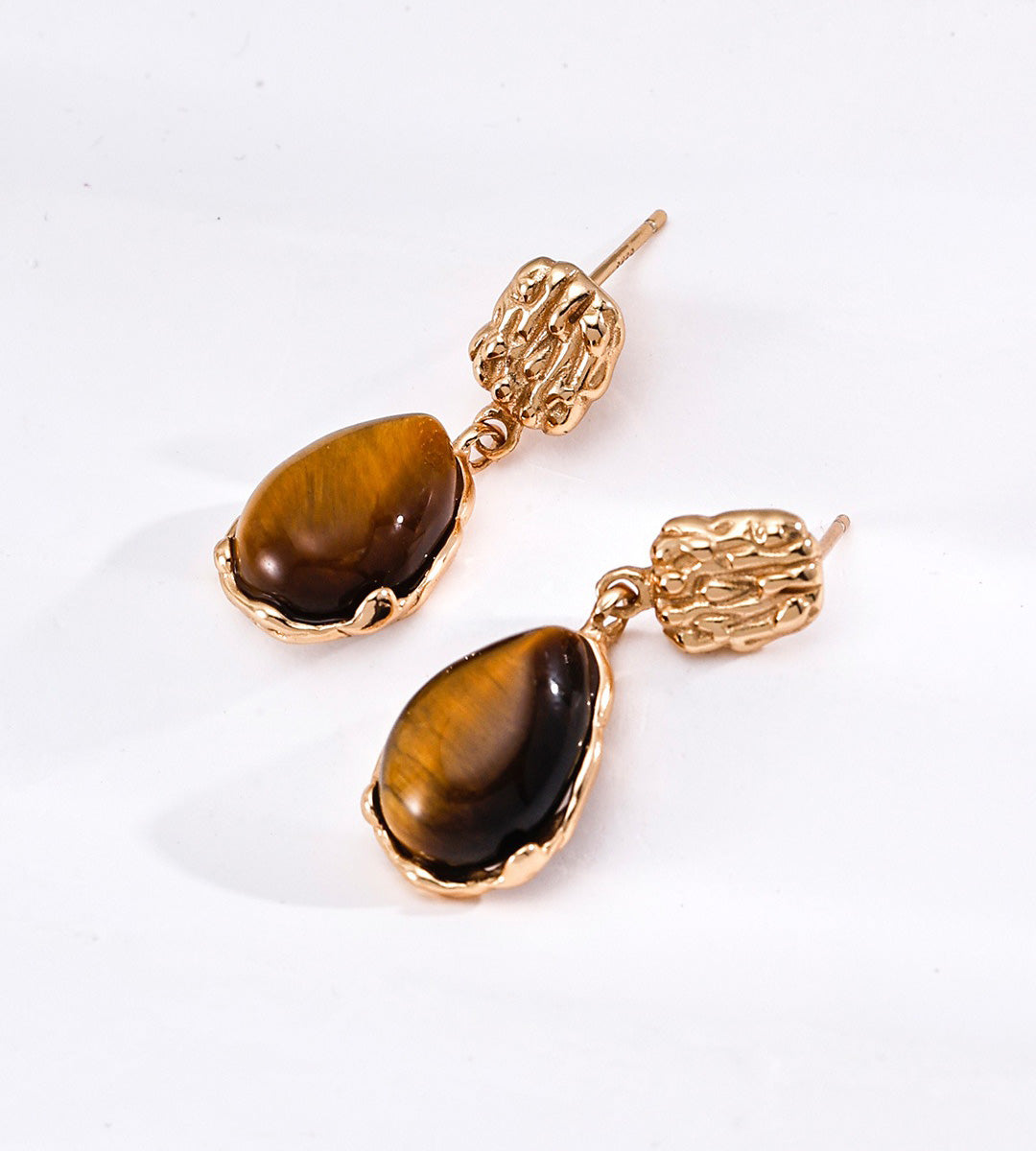 A pair of 18K gold-plated S925 silver drop earrings featuring polished brown tiger's eye stones in textured gold bezel settings | BUCKLE Collective