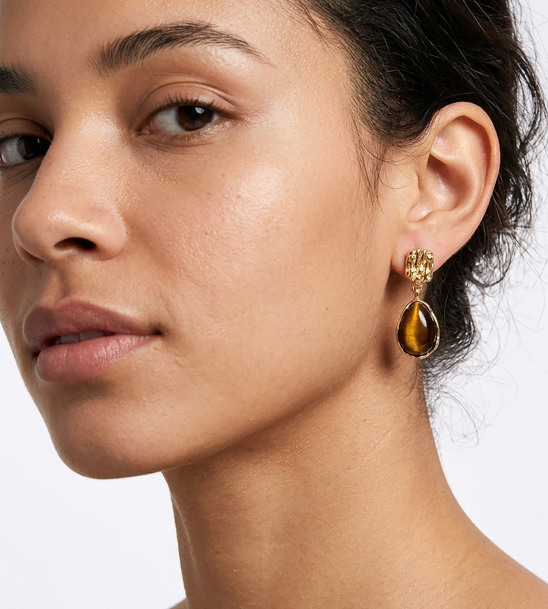 A close-up of a woman's ear wearing 18K Gold-Plated S925 Silver Teardrop Tiger's Eye Drop Earrings | BUCKLE Collective