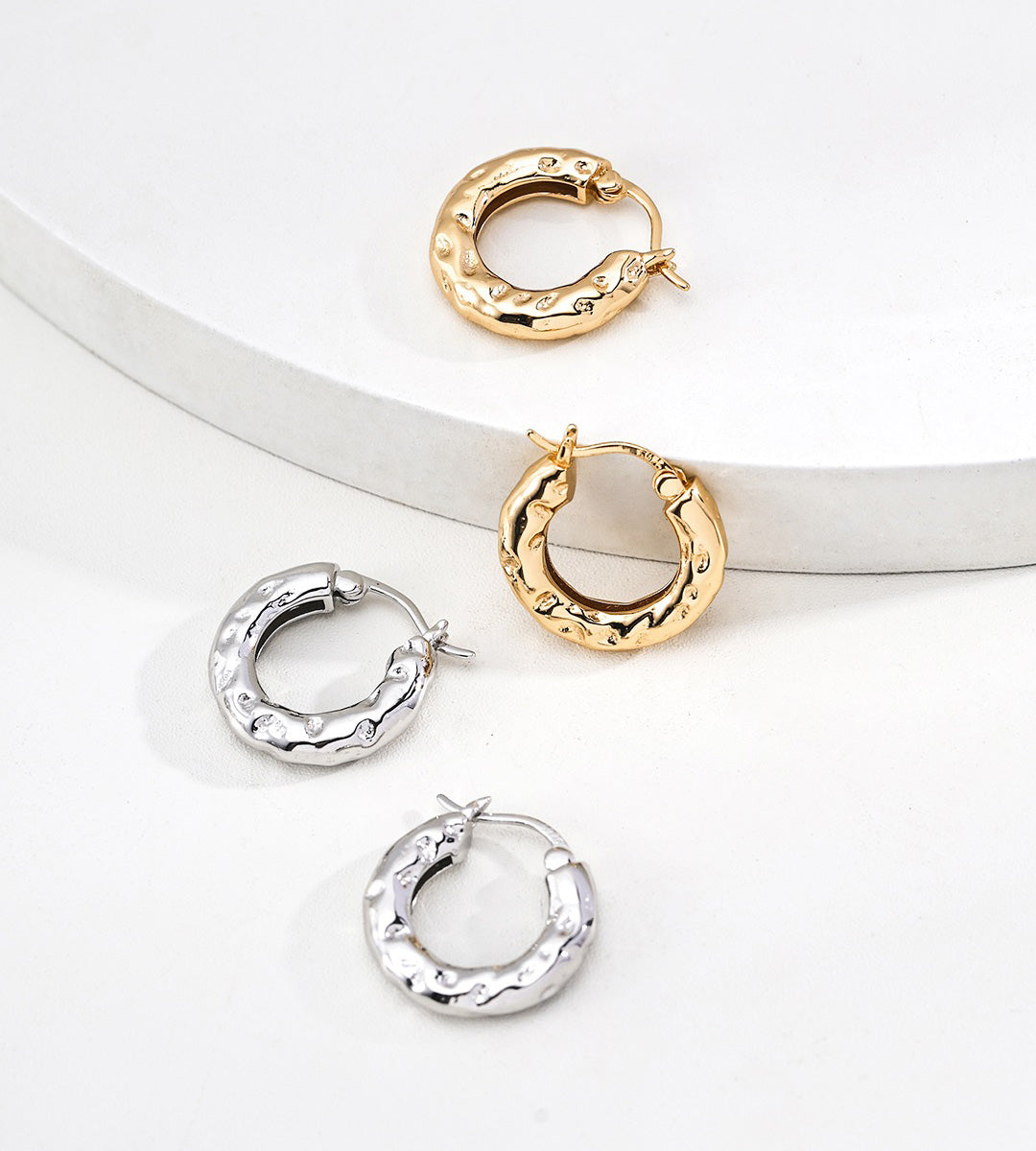 Two pairs of textured 18K gold-plated and 18K white-gold-plated S925 silver hoop earrings with a hammered finish, displayed on a clean white background.