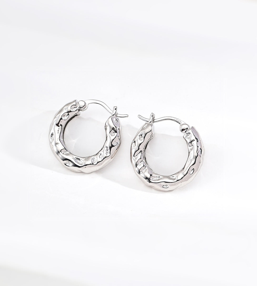 A pair of textured 18K white-gold-plated S925 silver hoop earrings with a hammered finish, displayed on a clean white background.