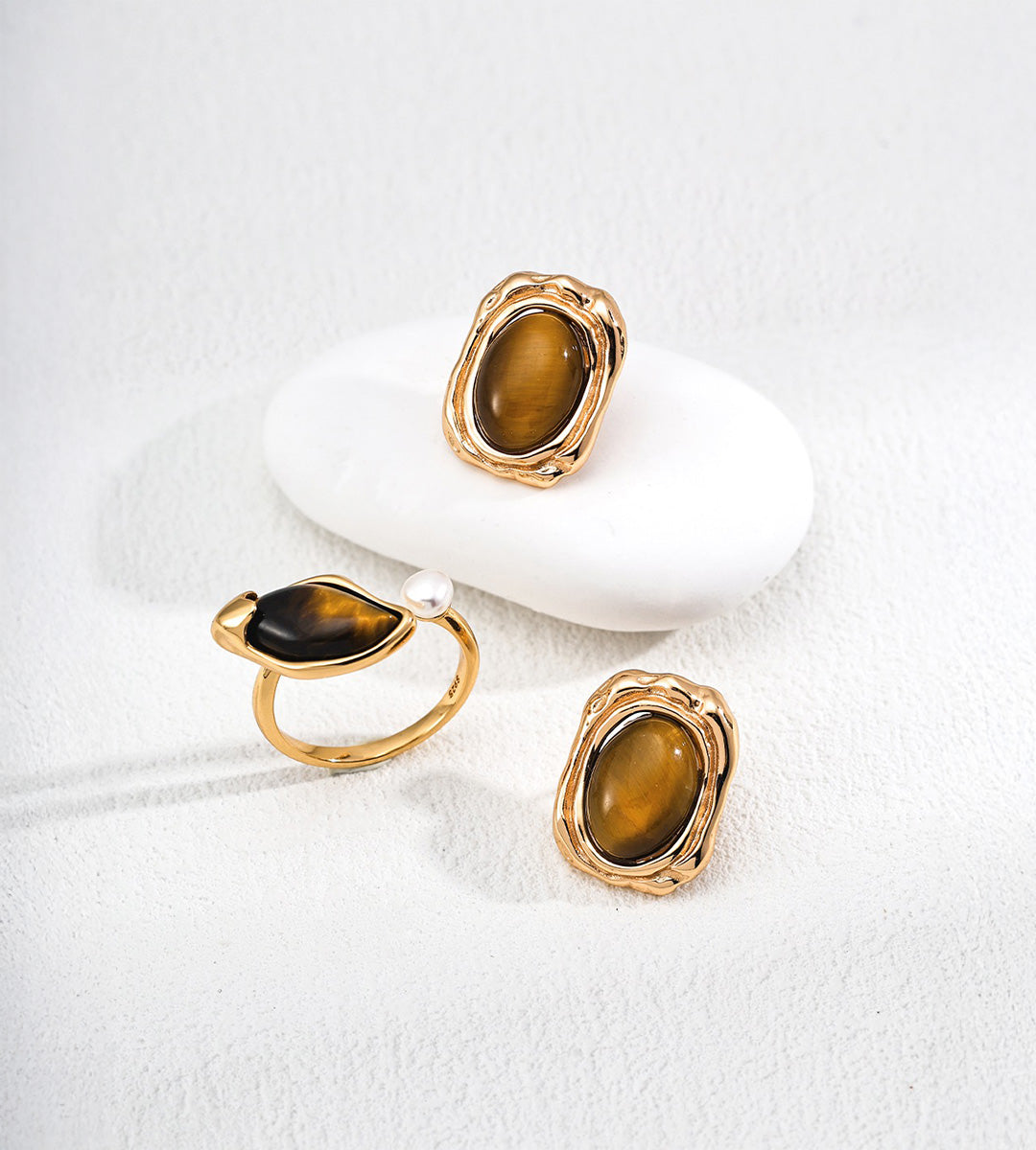 Tiger’s eye and freshwater pearl open ring in Vintage Gold, displayed beside two oval tiger’s eye earrings.