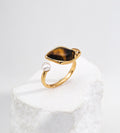 18K gold-plated S925 silver open ring with leaf-shaped tiger’s eye and a freshwater pearl on a white stone display.