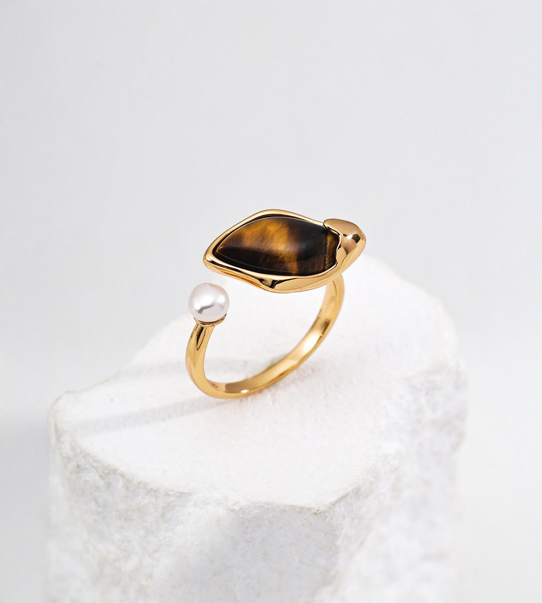 18K gold-plated S925 silver open ring with leaf-shaped tiger’s eye and a freshwater pearl on a white stone display.
