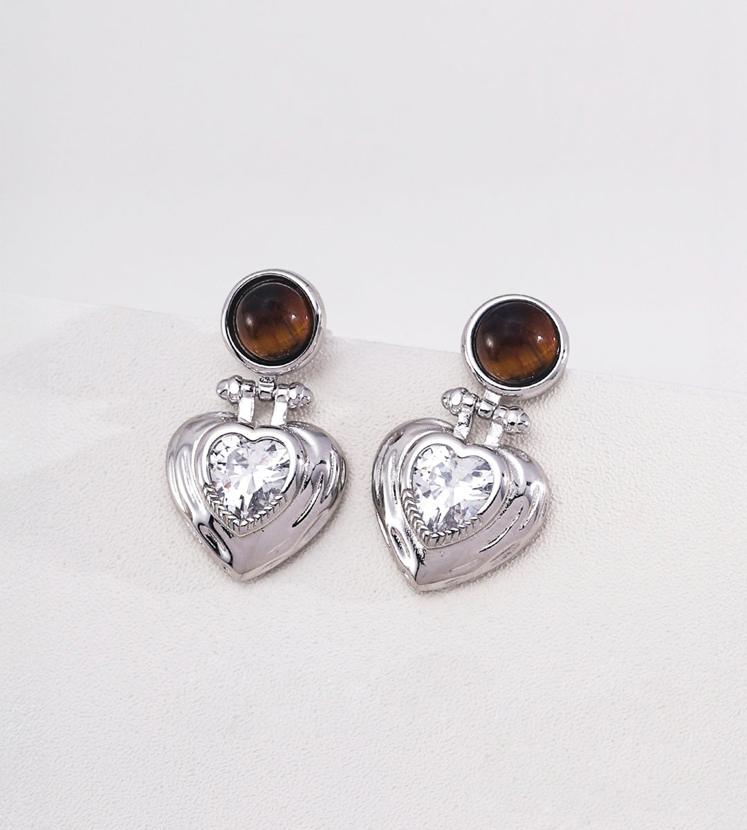 Tiger's eye and heart-cut cubic zirconia heart drop earrings in 18K white gold plating — round tiger's eye cabochon stud with puffed gold heart pendant and sparkling CZ centre stone, S925 silver, BUCKLE Collective