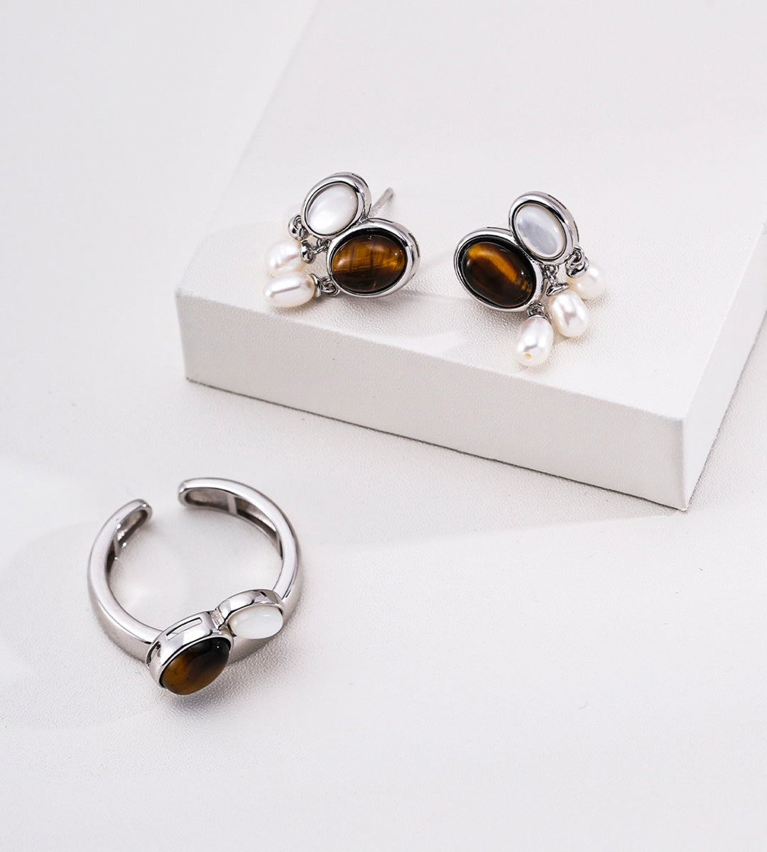 White-Gold-plated jewelry set featuring an open ring and matching drop earrings, each with an oval tiger's eye stone, mother-of-pearl, and three small white natural freshwater pearl drops, 18K Gold-Plated on S925 Sterling Silver | BUCKLE Collective