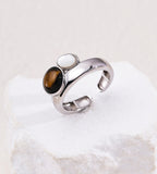 An 18K White-Gold-Plated open cuff ring featuring two oval inlays: a prominent brown tiger's eye stone and a smaller mother-of-pearl | BUCKLE Collective