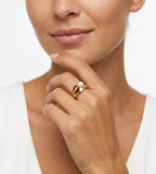 A close-up of a model wearing an 18K gold-plated S925 Silver ring with a polished oval tiger's eye stone and a small white mother-of-pearl accent on her finger | BUCKLE Collective