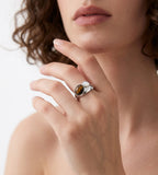 A woman wearing an 18K White-Gold-Plated open cuff ring featuring a brown tiger's eye stone and a smaller mother-of-pearl | BUCKLE Collective