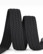 A close-up of a black braided elastic belt with a textured chevron weave, coiled on a white background.