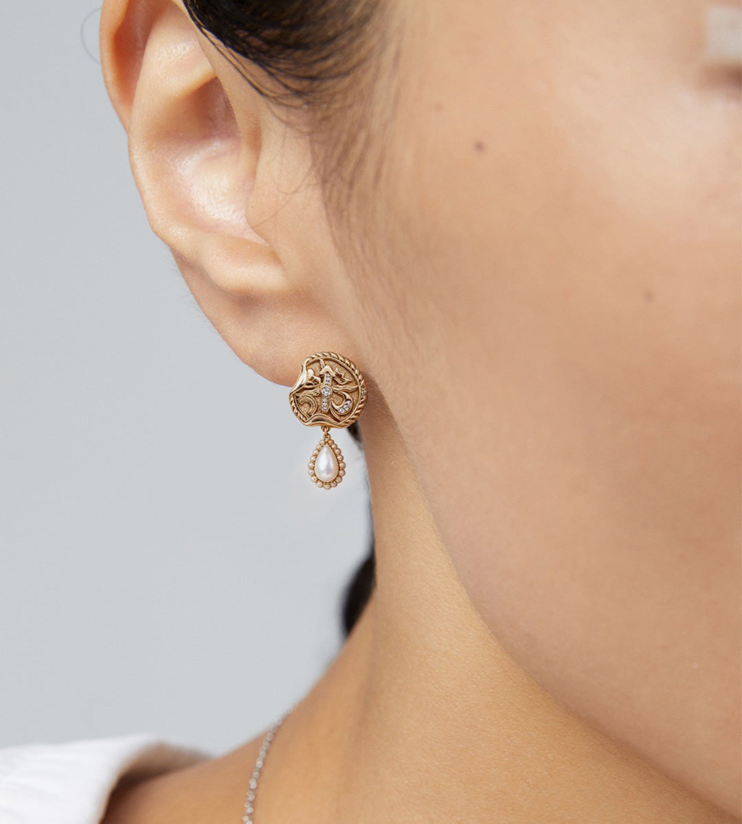 A close-up lifestyle shot of a model's ear wearing 18K gold-plated S925 Silver earrings with Vintage Gold Clock Motif Drop Earrings