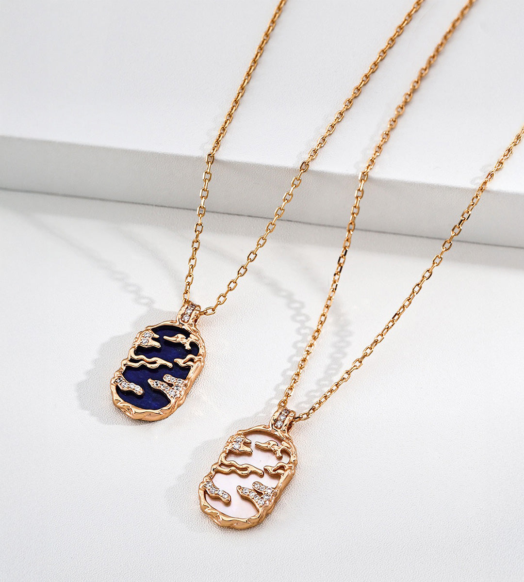 Lapis lazuli and mother-of-pearl landscape necklaces side by side, with gold-tone openwork scenery and cubic zirconia accents