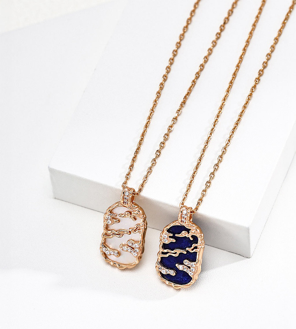 Mother-of-pearl and lapis lazuli landscape pendant necklaces, left to right, with gold-tone mountain and cloud openwork and cubic zirconia accents