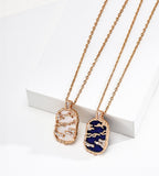 Mother-of-pearl and lapis lazuli landscape pendant necklaces, left to right, with gold-tone mountain and cloud openwork and cubic zirconia accents