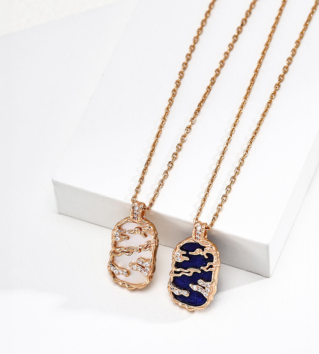 Mother-of-pearl and lapis lazuli landscape pendant necklaces, left to right, with gold-tone mountain and cloud openwork and cubic zirconia accents