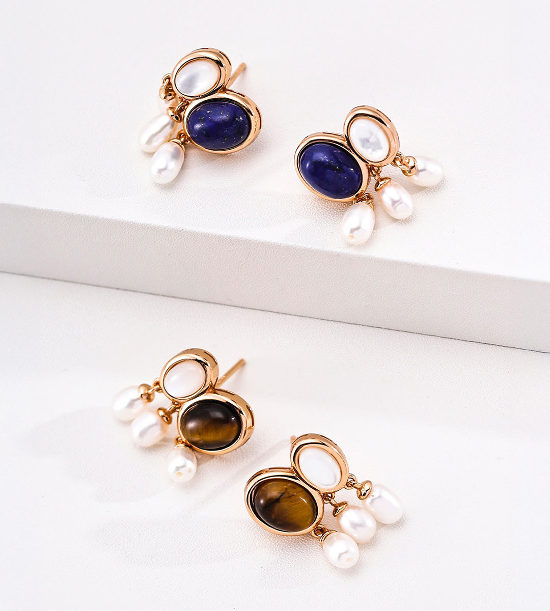 Four gold-plated drop earrings with oval lapis lazuli and tiger's eye stones and three small white pearl drops