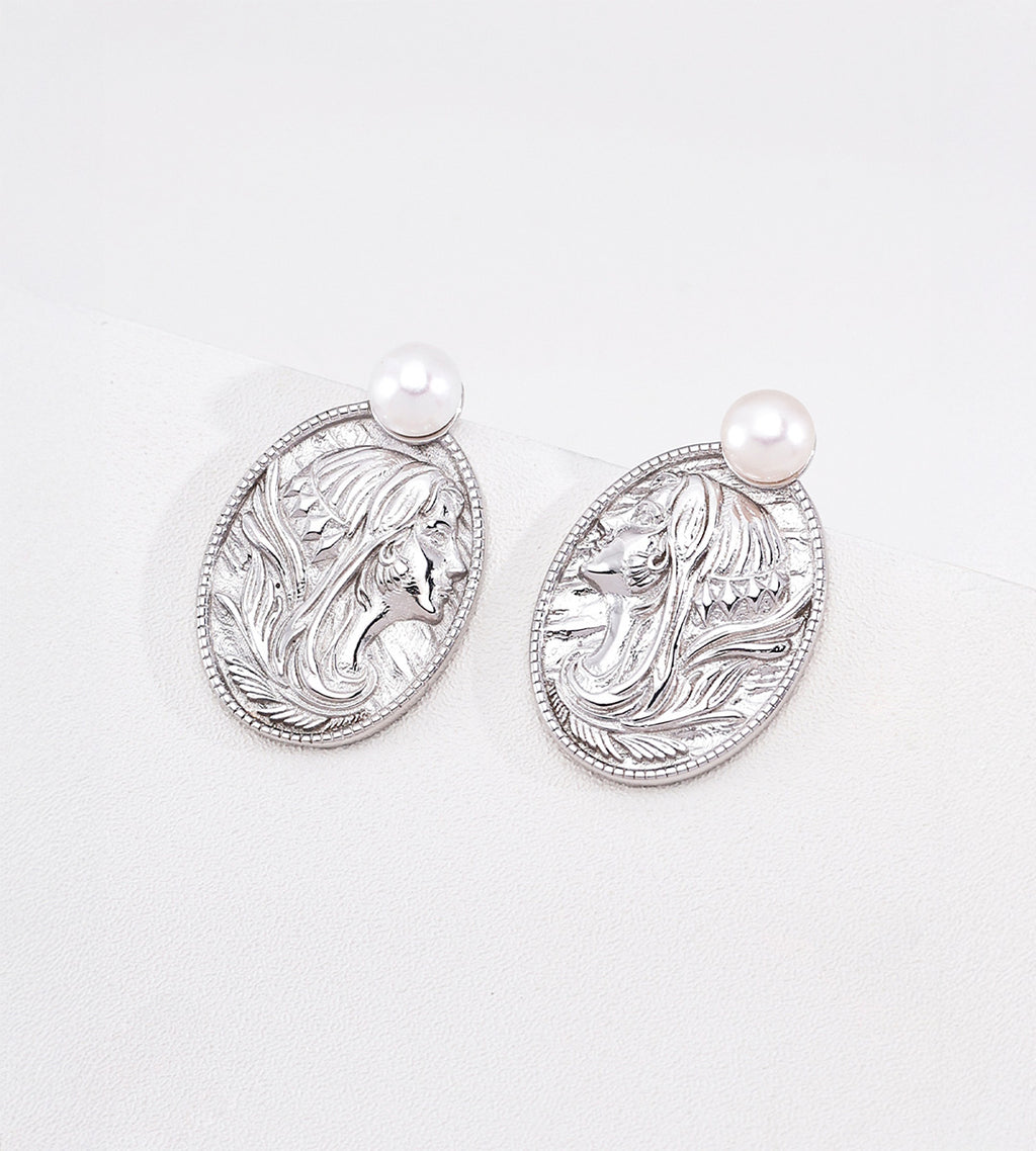 Silver-tone portrait pearl earrings with raised lady profiles on oval medallions, each topped with a white pearl.